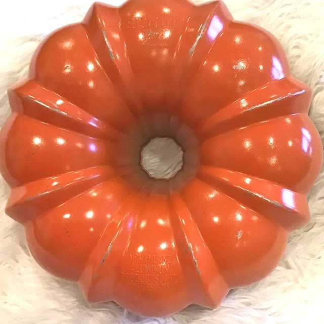 Bundt cake pan with original box — orange exterior; dark nonstick interior in supporting view